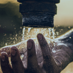 mãos com agua caindo de um cano